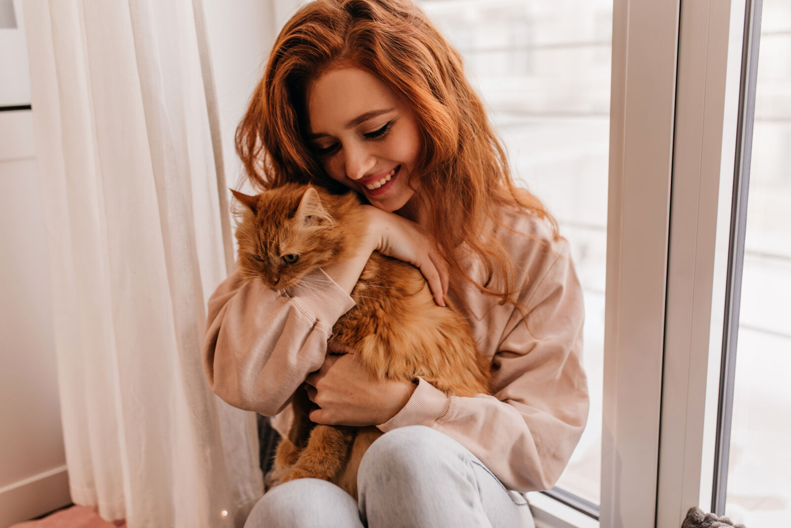 Dziewczyna w rudych włosach przytula rudego kota